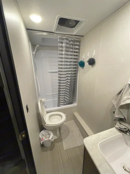 Compact RV rental bathroom with shower, toilet, and sink, designed for efficient travel living.. Keystone Hideout 2021