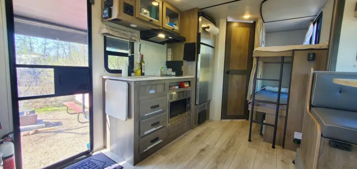 Step inside this modern RV rental featuring a full kitchenette, comfy bunk beds, and outdoor camp views.. Forest River Surveyor Legend 2022