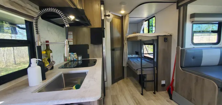 Compact RV rental interior featuring kitchen, bunk beds, and dinette area, showing efficient living space.. Forest River Surveyor Legend 2022