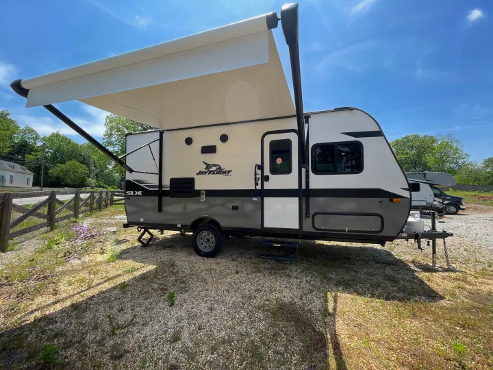 A modern Jay Flight SLX travel trailer, great for rv rental, is parked on gravel with its awning open under a clear sky.. Jayco Jay Flight 2022
