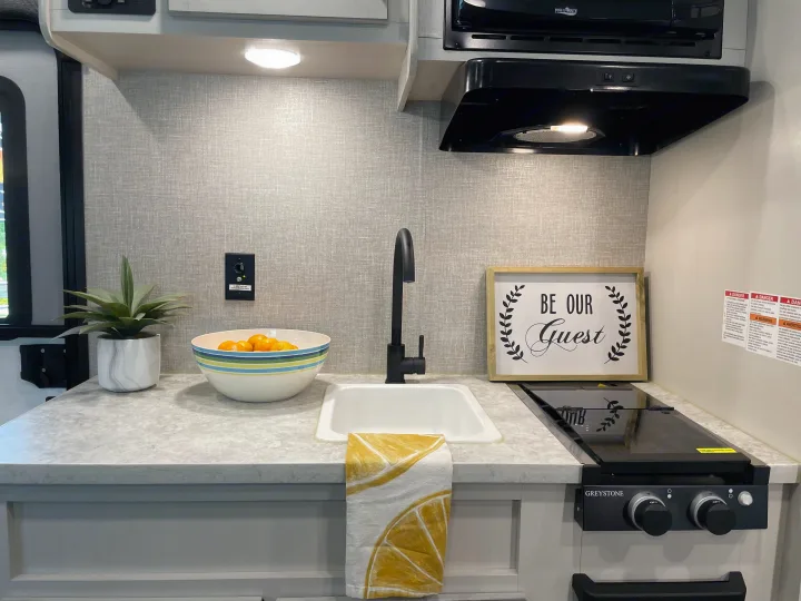 Welcoming RV rental kitchen with modern sink, Greystone stove, High Pointe microwave, patterned backsplash, and inviting decor.. Jayco Jay Flight 2022