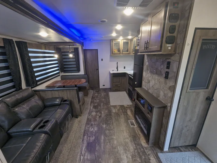 Cozy RV rental interior: living area with sofa, dining booth, full kitchen, and fireplace. Modern and well-appointed.. Forest River Cherokee Wolf Pack Toy Hauler 2022
