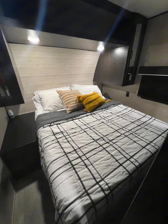 Inside an RV rental: a compact, cozy bedroom with a modern bed, overhead storage, and warm mood lighting.. Jayco Jay Flight 267BH 2023