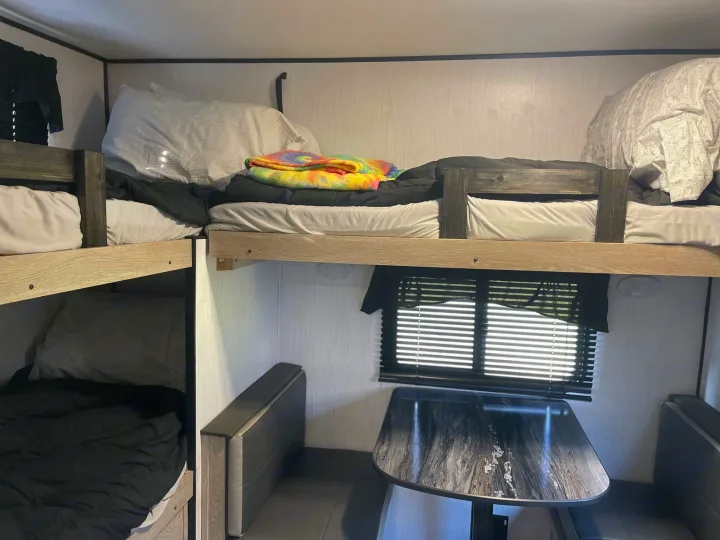 RV rental with stacked bunk beds on left, dinette table & seating on right. Cozy interior.. Heartland RVs Prowler 2022