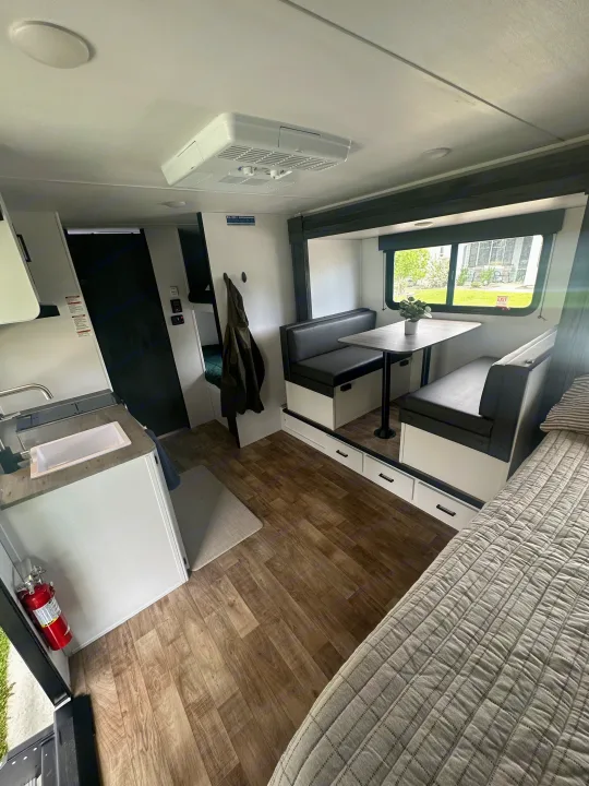 Modern RV rental interior: Dinette, kitchen, bed, and bunk beds. Cozy and functional compact living space.. Keystone RV Hideout 2023