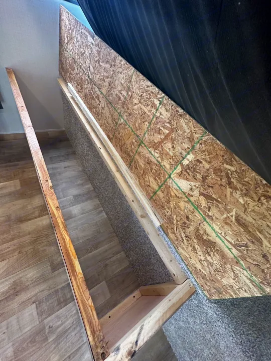 Building custom RV rental bed storage, featuring OSB base, wood frame, carpeted sides, and laminate flooring.. Keystone RV Hideout 2023