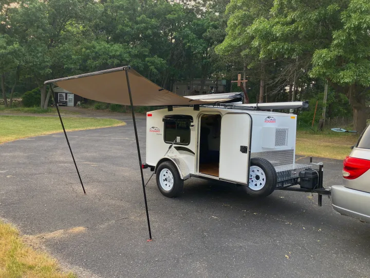 White teardrop trailer with extended awning, ideal for RV rental adventures. Ready for outdoor camping travel.. Runaway Campers Rangerunner 2021