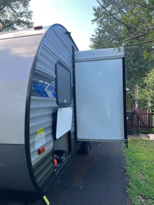 Side view of a grey and tan travel trailer RV rental with its large ramp door open, showing interior access.. Forest River Salem FSX 2022