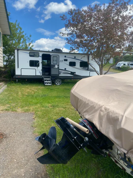 Kodiak travel trailer on grass, great for an rv rental getaway. Covered boat in foreground, another RV beyond.. Dutchmen Kodiak Ultra Lite 2020