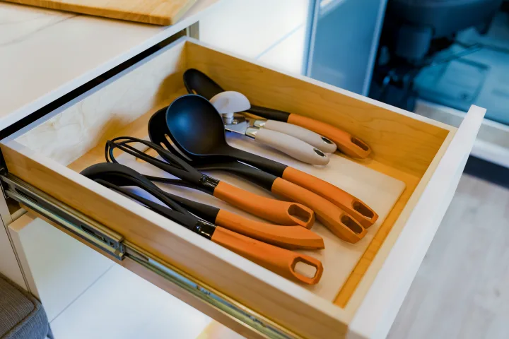 Organized kitchen utensils in an RV rental drawer, with black & orange handles on a clean white liner.. Dodge 1500 2023