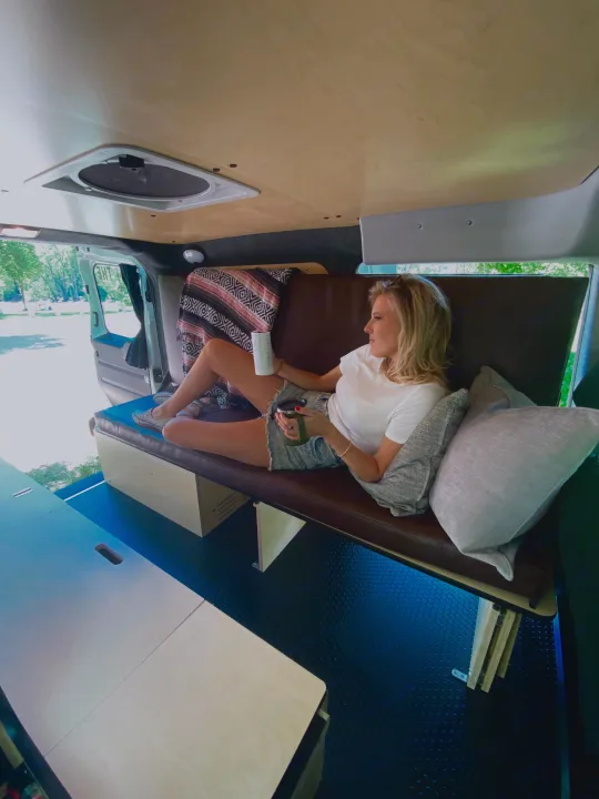 Experience comfort in this rv rental. Woman relaxing inside a thoughtfully designed mobile living space.. Dodge Promaster City 2020