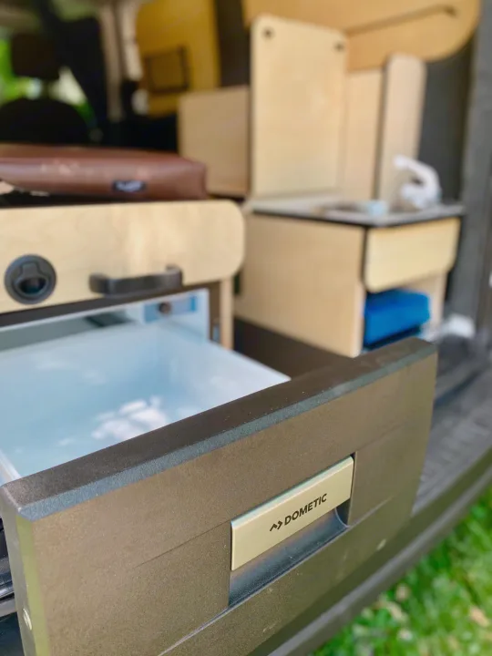 A Dometic drawer fridge/freezer is open in this modular camper van rv rental. Features organized storage.. Dodge Promaster City 2020