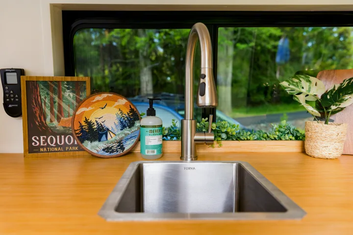 RV rental kitchenette features a Torva sink, Forious faucet, Mrs. Meyer's soap, and nature decor by a scenic window view.. Dodge 1500 2023