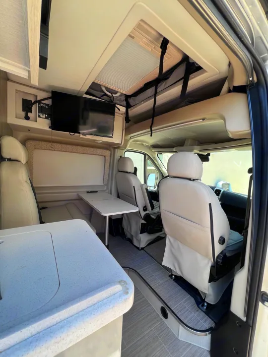 Modern rv rental interior, featuring a dinette, swivel seats, and TV, designed for comfort on your travels.. Thor Tellaro 2021
