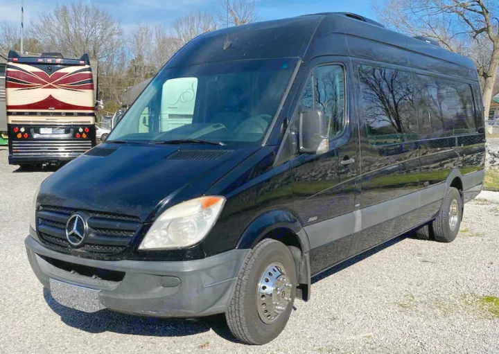 Black Mercedes-Benz Sprinter RV rental. This custom van is ready for adventure, parked on gravel next to another RV.. Mercedes-Benz Sprinter 2012