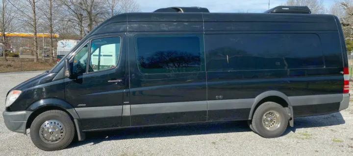 Side view of a black Mercedes Sprinter 3500 rv rental van, featuring tinted windows and a rooftop AC unit.. Mercedes-Benz Sprinter 2012