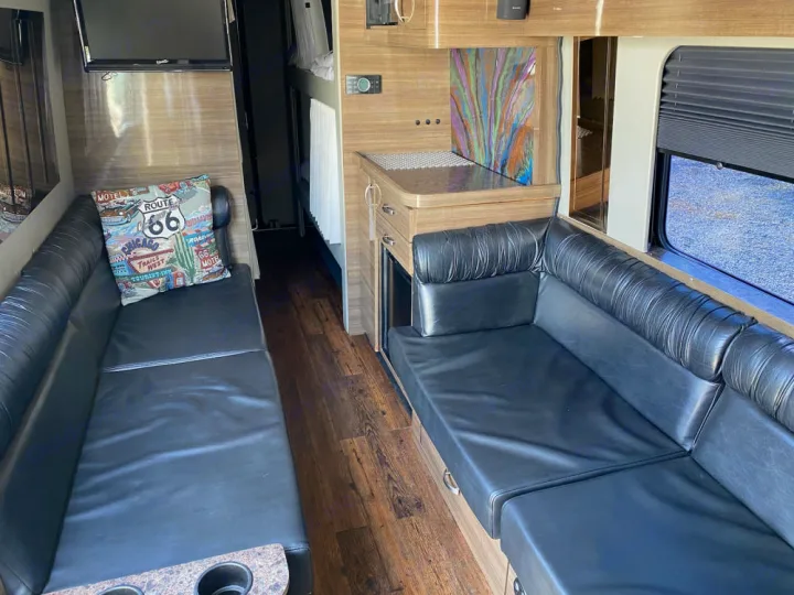 Inside this RV rental: plush black seating, sleek wood-look floors, a compact kitchen, and TV. Perfect for road trips!. Mercedes-Benz Sprinter 2012