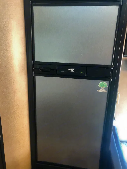 Dark grey Norcold RV refrigerator, common in an RV rental, showing controls & dual doors.. Dutchmen Kodiak Express 2017