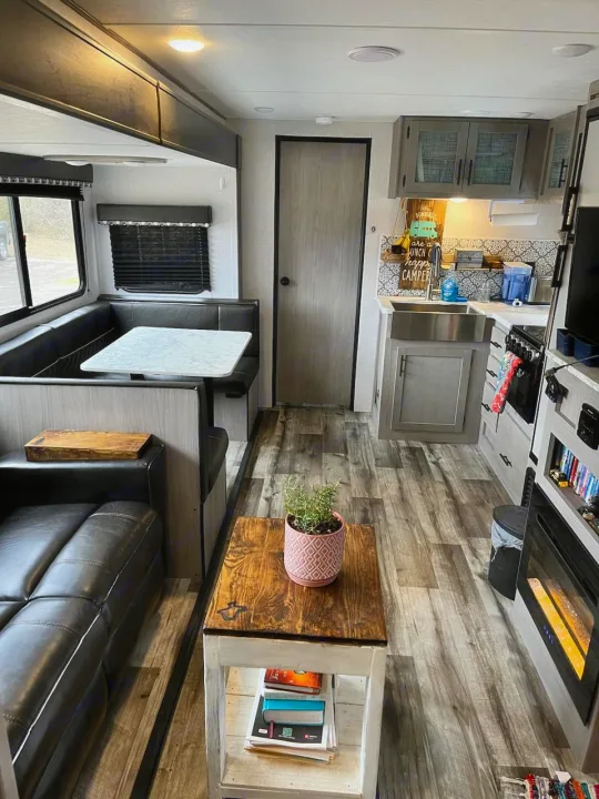 Step into this inviting RV rental interior, featuring a cozy living space, dining booth, and a compact kitchen.. Dutchmen Coleman Light 2021