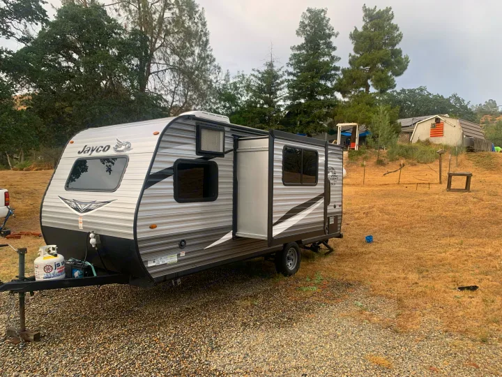 This Jayco RV rental travel trailer, with its slide-out extended, awaits adventure in a dry field.. Jayco Jay Flight SLX 2020