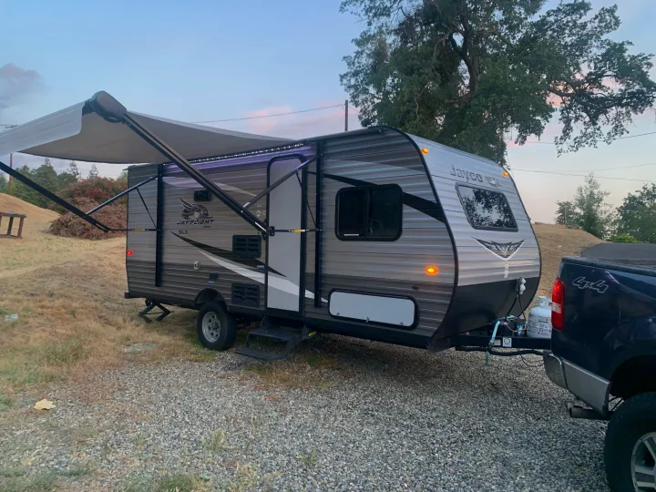 Jayco travel trailer RV rental with extended awning & LED lights, hitched to a truck on gravel, ready for adventure.. Jayco Jay Flight SLX 2020