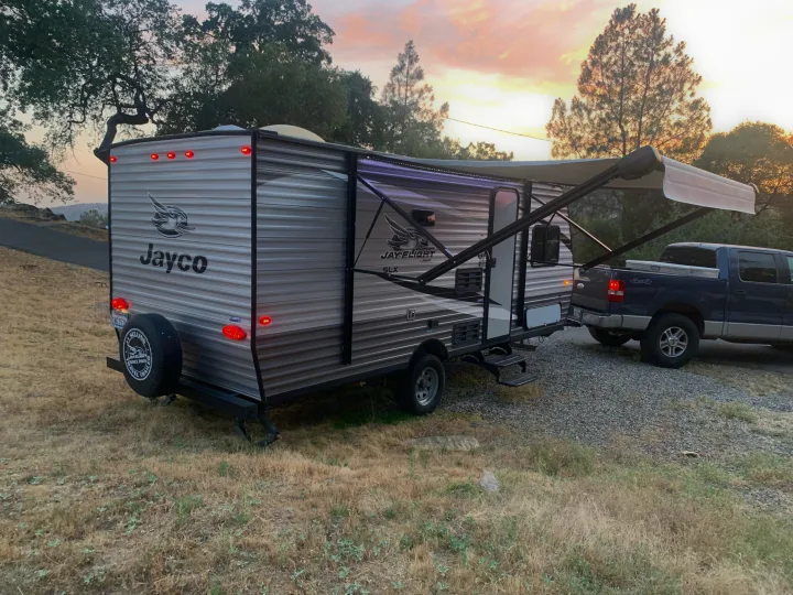 Enjoy an **rv rental**! This Jayco travel trailer, hitched to a truck, is set against a beautiful sunset, ready for adventure.. Jayco Jay Flight SLX 2020