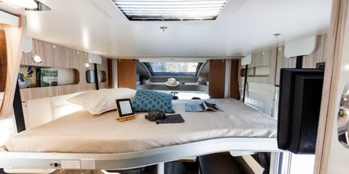 Comfortable RV rental bedroom interior with a bed, e-reader, and TV, offering a cozy space for travel.. Elnagh 582 2023