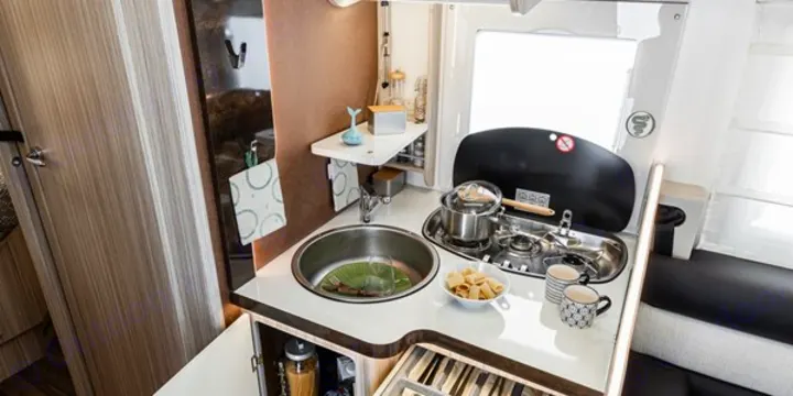 This compact RV rental kitchen features a stainless steel sink, two-burner stove, and storage, ideal for cooking on the go.. Elnagh 582 2023
