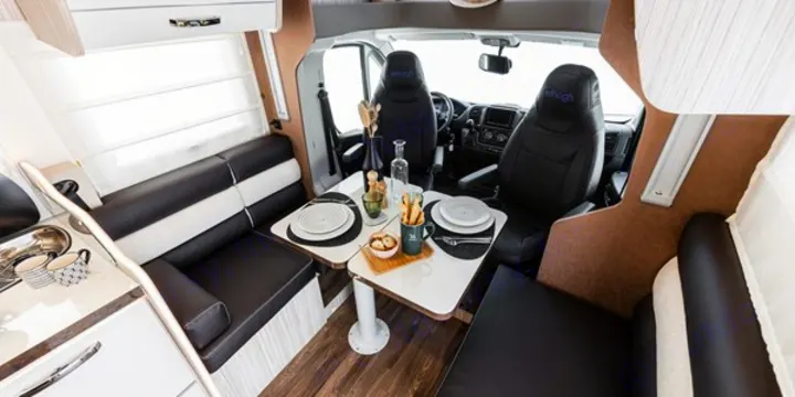 An inviting RV rental interior featuring a practical dinette, compact kitchen, and driver's cabin. Ready for adventure.. Elnagh 582 2023