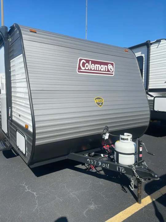Grey Coleman travel trailer for RV rental, with propane tank, parked on asphalt under a clear sky.. Coleman Lantern 17B 2023