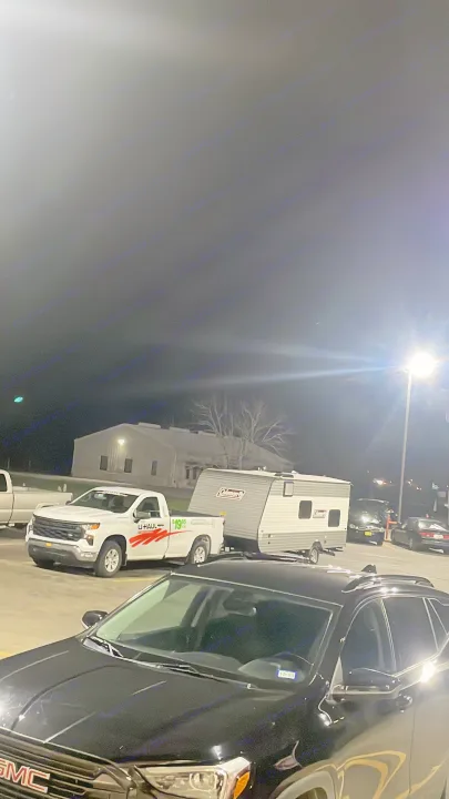 Night scene: A U-Haul truck towing a Coleman travel trailer (an RV rental) parked near a GMC truck.. Coleman Lantern 17B 2023