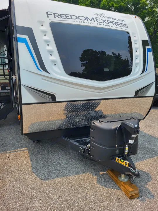 Front of a white Coachmen Freedom Express travel trailer rv rental, with a large window, graphics, and hitch area with propane tanks.. Coachmen Freedom Express Ultra Lite 257BHS 2023