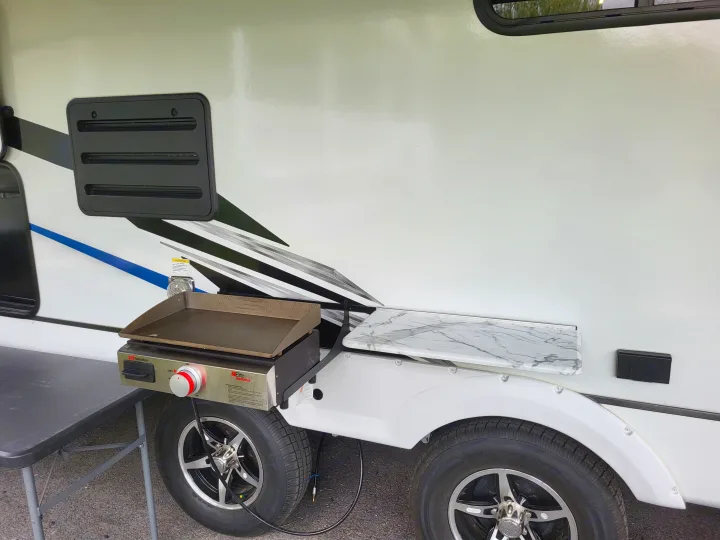 RV rental with a convenient outdoor griddle, folding table, and side shelf for easy campsite cooking.. Coachmen Freedom Express Ultra Lite 257BHS 2023