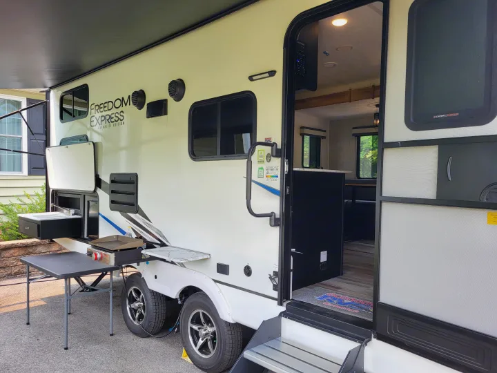This Freedom Express RV rental features an outdoor kitchen, extended awning, and inviting interior, perfect for camping.. Coachmen Freedom Express Ultra Lite 257BHS 2023