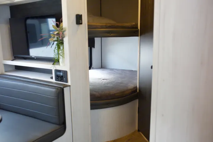 RV rental interior: living area with TV, upholstered dinette, and dedicated bunk beds visible.. Heartland Trail Runner 2022
