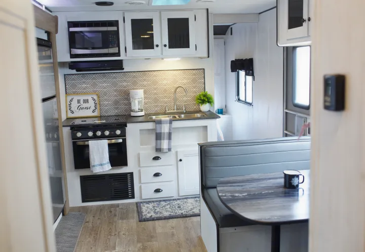 Modern RV rental kitchen & dinette area, featuring microwave, stove, sink, coffee maker, and comfortable seating.. Heartland Trail Runner 2022