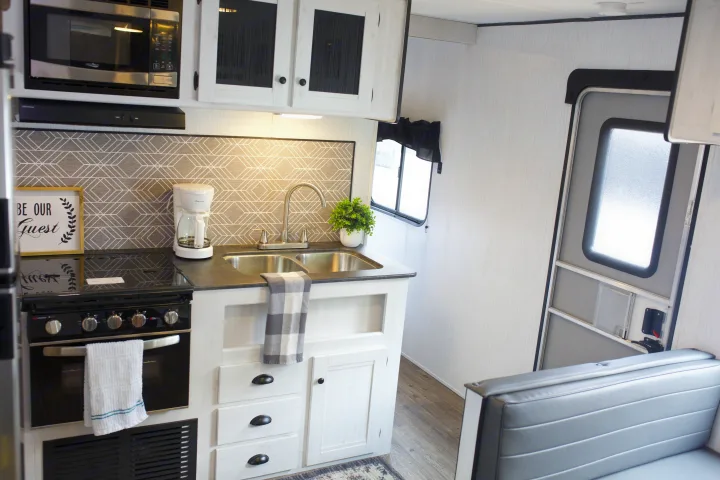 Explore this RV rental's modern kitchen: microwave, stove, sink, coffee maker, and dinette seating.. Heartland Trail Runner 2022