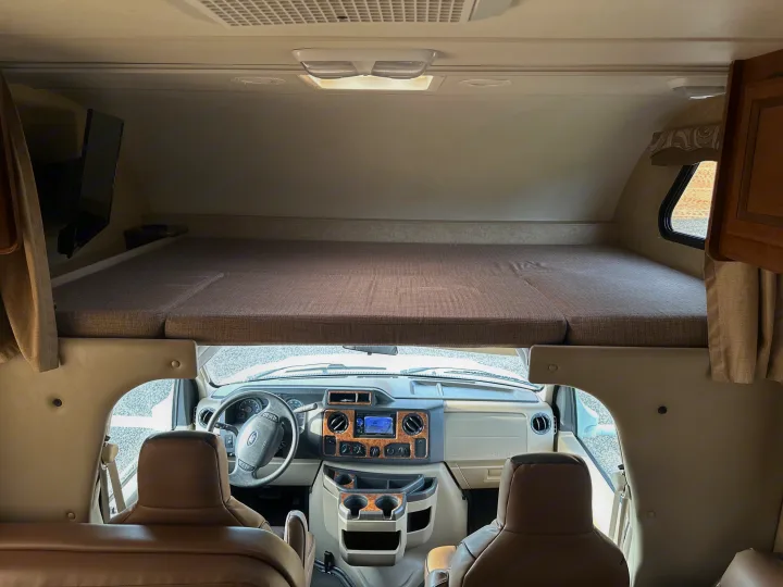 Spacious interior of an RV rental, featuring the cab-over bed and a clear view of the cockpit.. Thor Chateau 2015