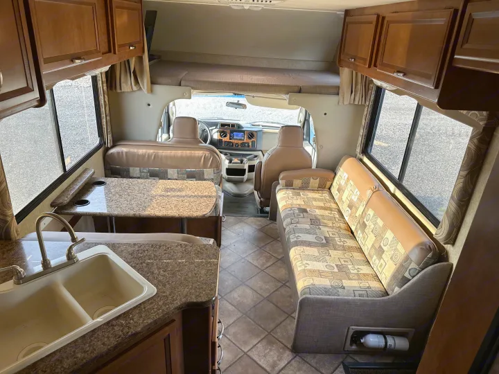 Spacious RV rental interior with kitchen, dinette, living area, over-cab bunk, and cockpit view.. Thor Chateau 2015