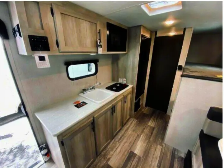 Spacious RV rental interior featuring a full kitchen with microwave, sink, and stove, plus bunk beds. Ideal for travel.. KZ Classic 2022