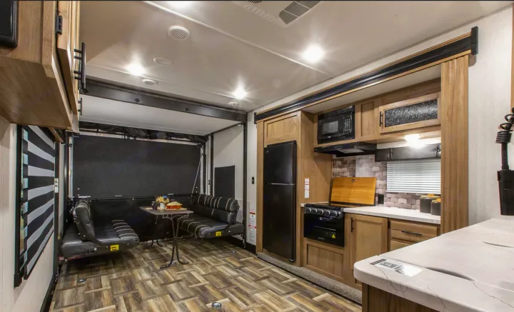 RV rental: Modern interior with a well-equipped kitchen (fridge, microwave, stove), dining area, and wood-patterned flooring.. Forest River Cherokee Wolf Pack 2020