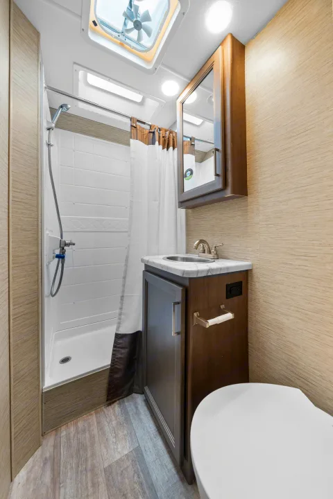 Compact RV rental bathroom features a shower, vanity, toilet, and ceiling vent, offering convenience on the go.. Thor Coleman 2023