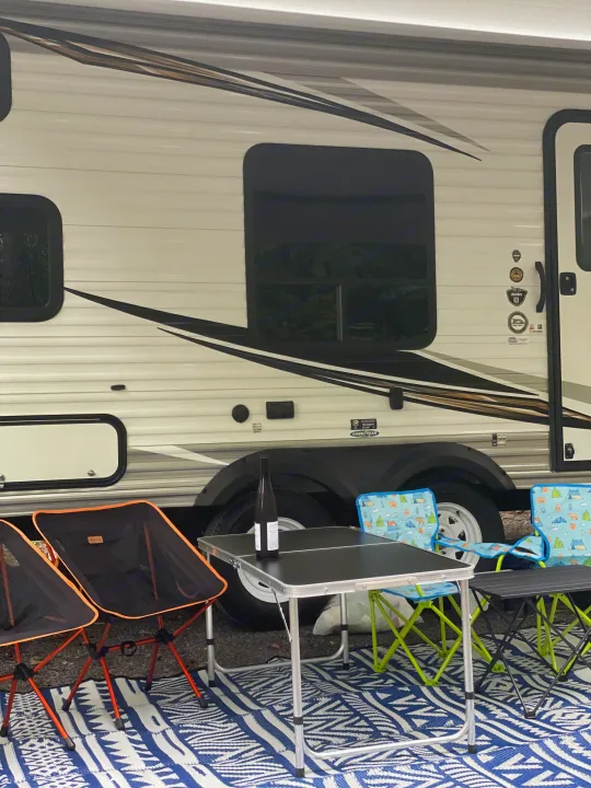 RV rental campsite setup: outdoor rug, folding chairs, and table for relaxing by the travel trailer.. Jayco Jay Flight SLX 2019