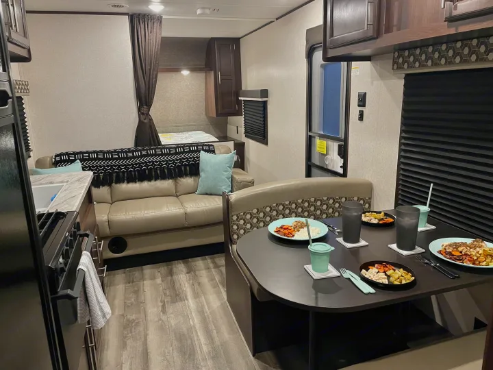 Cozy RV rental interior with kitchen, dining area, couch, and bunk beds, set for a meal.. Jayco Jay Flight SLX 2019