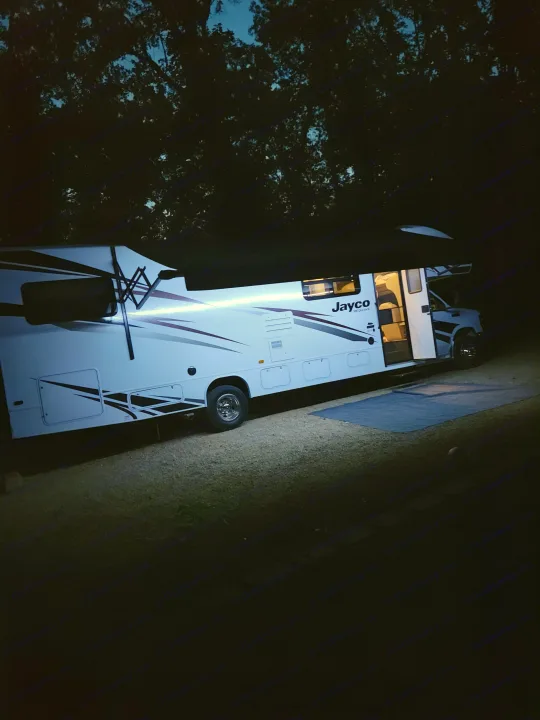 **RV rental** illuminated at a serene **nighttime** campsite, perfect for **outdoor** adventures.. Jayco Redhawk 2020