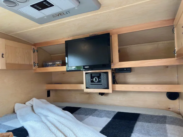 Inside a compact rv rental: warm wood interior, overhead AC, TV, stereo, and a snug bed. Ready for travel.. Little Guy Little Guy Trailer 2013