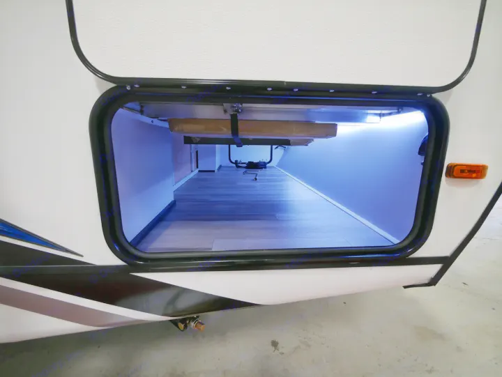Spacious RV rental storage compartment with blue LED lighting and wood-look floor, perfect for gear.. Coachmen 257BHS 2022