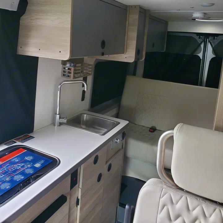 This RV rental features a bright interior with a compact kitchenette, sink, overhead cabinets, and comfortable patterned rear seating.. Winnebago Solis 2022