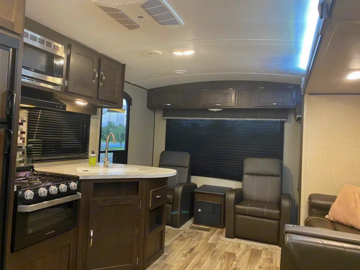 Modern RV rental interior with a full kitchen, comfy recliners, and ample cabinet space, ideal for travel.. Keystone RV Hideout 2023