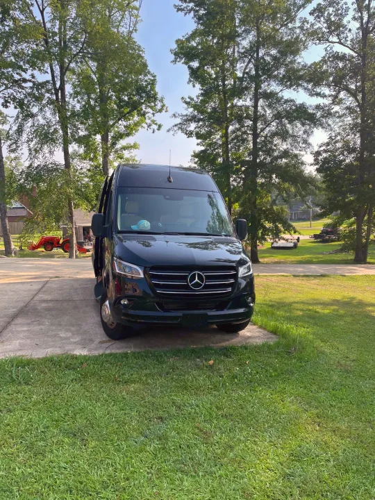 Black Mercedes-Benz Sprinter RV rental van on a driveway, surrounded by green grass & trees.. Mercedes-Benz Sprinter 2023